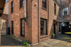 A brick building with large windows and a small garden area.