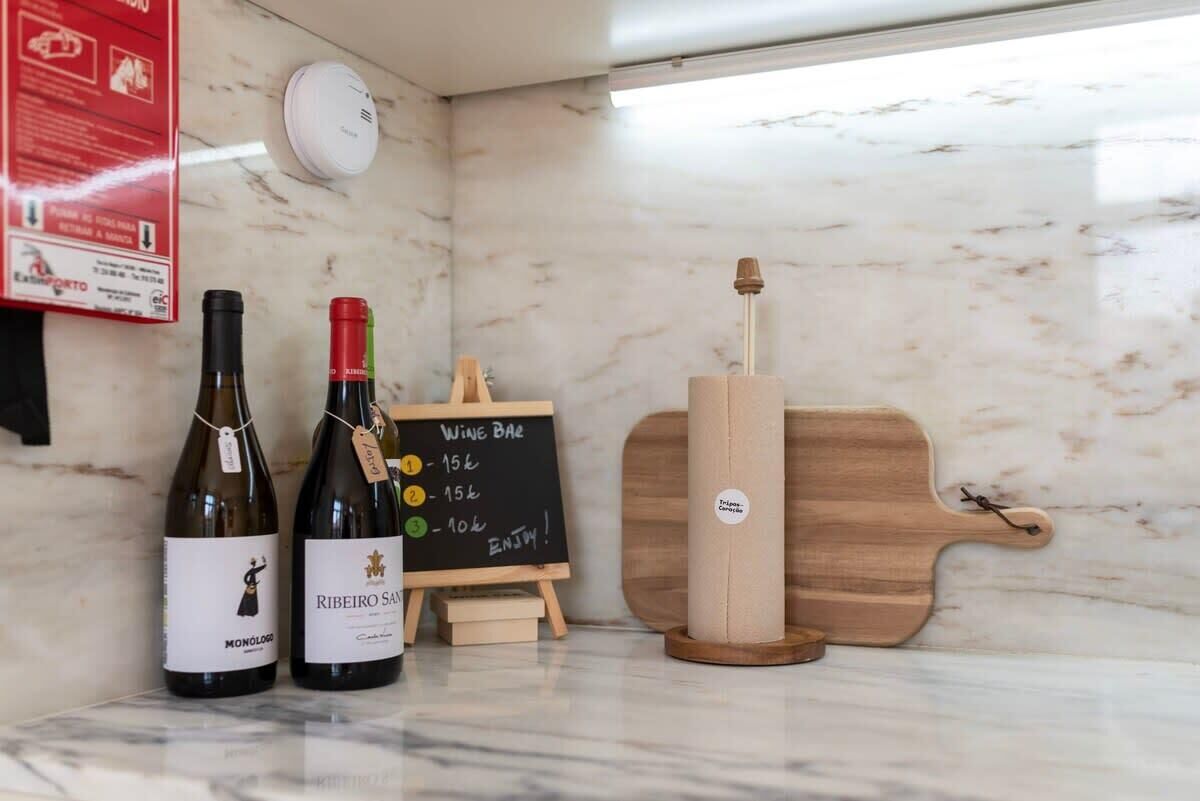 Two wine bottles, a wooden wine rack, and a chalkboard menu on a marble countertop.