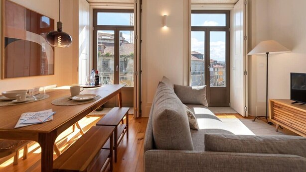 Een moderne woonkamer met een houten eettafel, bankjes, een bank en een tv-meubel.
