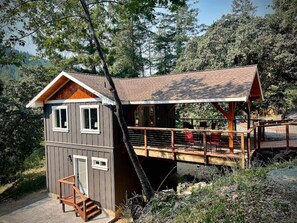 A cabin with a wooden deck and a small staircase leading to a door.