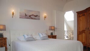 Une chambre à coucher avec un grand lit, deux tables de chevet avec des lampes, une armoire en bois et un tableau au mur.