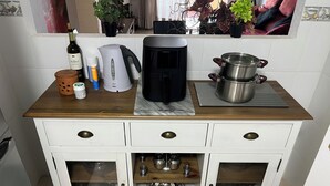 Una cucina con un piano di lavoro in legno, una macchina da caffè, un bollitore, una bottiglia di vino e una pentola sul fornello.
