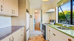 A compact kitchen with a window, a stove, and a sink.