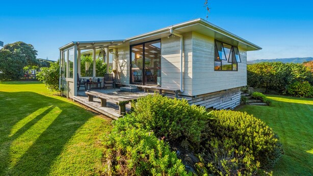A modern house with a covered porch, large windows, and a well-maintained lawn.