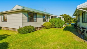 A two-story mobile home with a green roof, a small garden, and a clear blue sky.