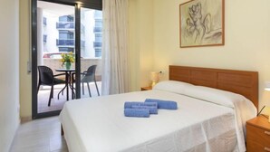 Ein Hotelzimmer mit Bett, Nachttisch, Lampe, einem Gemälde an der Wand und Blick auf den Balkon.