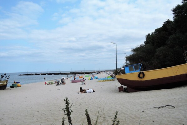 Relax on the sandy shore with access to the pier and a moored boat, perfect for a leisurely day by the sea.