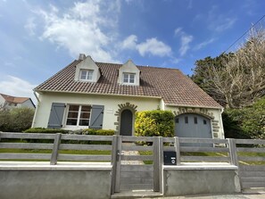 A two-story house with a tiled roof, a gated entrance, and a mailbox.