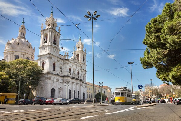 Eine historische Kathedrale mit filigraner Architektur, einer Straßenbahnlinie und blauem Himmel.