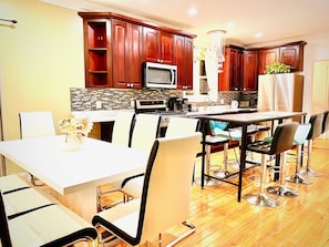 Una cocina moderna con armarios de madera, microondas y comedor con una mesa y sillas blancas.