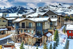 Un hôtel à plusieurs étages offrant une vue sur les pistes de ski, doté d’une façade en pierre et de nombreux balcons.