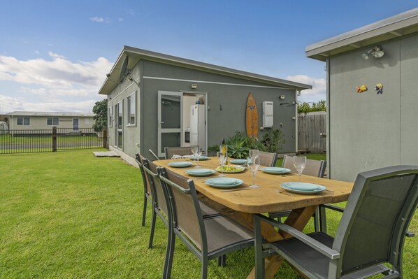 Un patio con una mesa de madera dispuesta para comer, rodeado de sillas de metal.