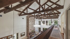 Un loft espacioso con vigas de madera a la vista, chimenea de ladrillo y vistas al exterior.