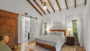 Un dormitorio con una cama de madera, una mesita de noche, un aparador y vistas al exterior a través de una ventana.