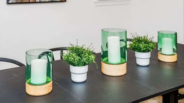 Un comedor con una lámpara de techo moderna, arte abstracto y plantas en macetas sobre la mesa.