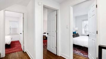 Un couloir mène à deux chambres, chacune étant équipée d’un lit et d’une fenêtre.