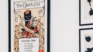 Un cartel enmarco de 'El Gato Negro' fechado diciembre de 1896, una cama con ropa blanca, una almohada negra y un cabecero de madera.