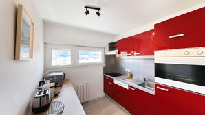 A modern kitchen with red cabinets, a built-in oven, and a window providing natural light.