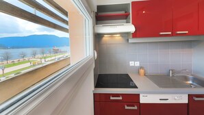 A compact kitchen with a window view, a built-in stove, and red cabinets.