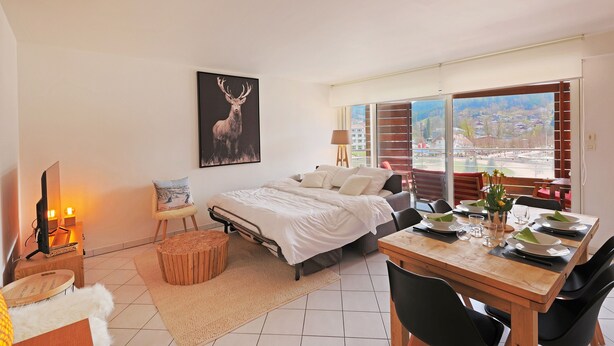 A modern bedroom with a bed, a desk, and a dining area.