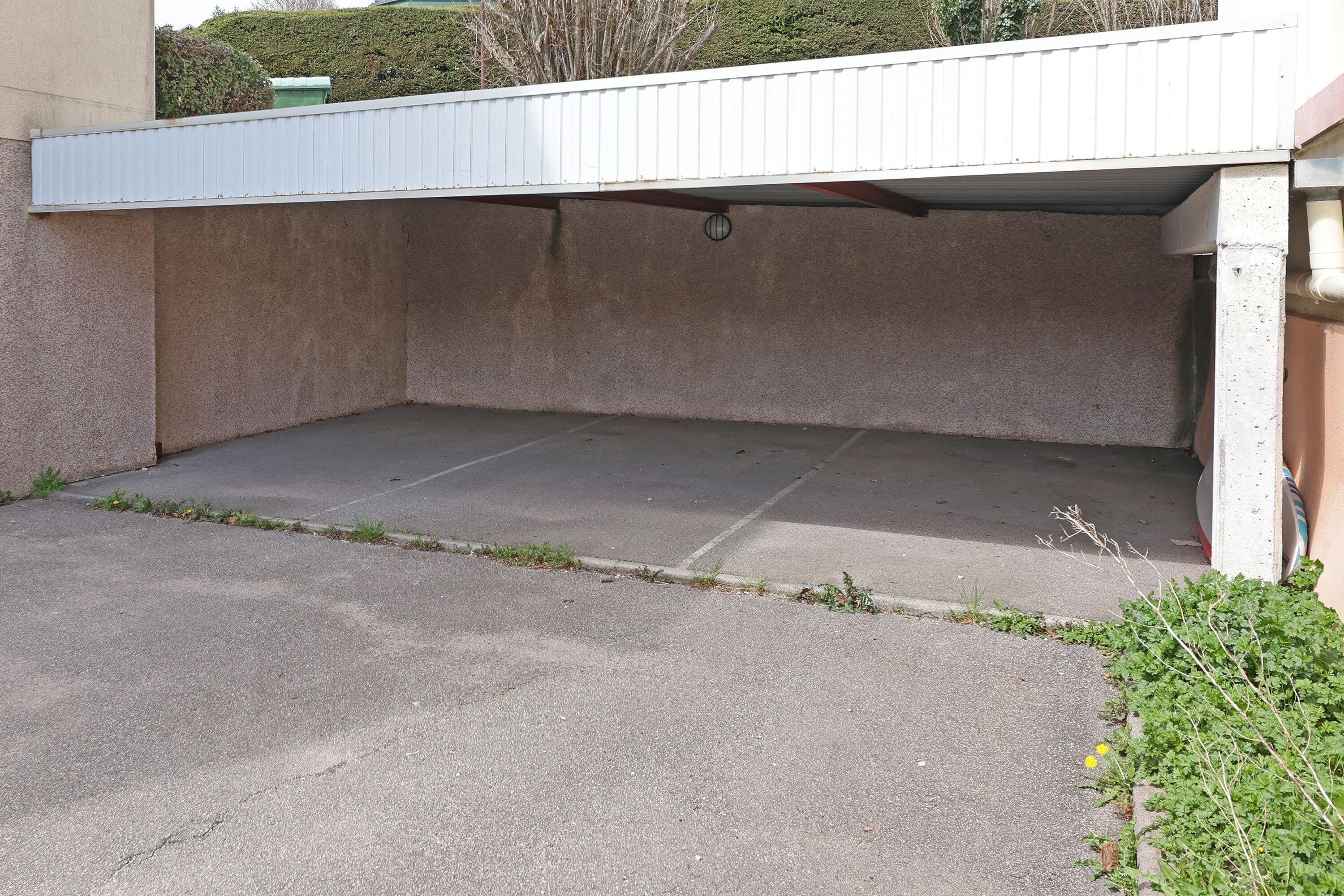 A parking area with a concrete floor and a white roof.
