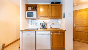 A compact kitchen with white appliances, wooden cabinets, and a small countertop.