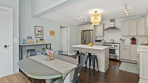 A modern kitchen with white cabinets, stainless steel appliances, and a central island with bar stools.