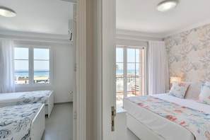 A hotel room with two beds, a balcony with a view of the sea, and a patterned wallpaper. - Chalet Santa Ana 24 by VillaGranCanaria (Playa del Ingles)