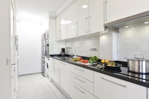 A modern kitchen with white cabinets, a black countertop, and stainless steel appliances. - Chalet Santa Ana 24 by VillaGranCanaria (Playa del Ingles)
