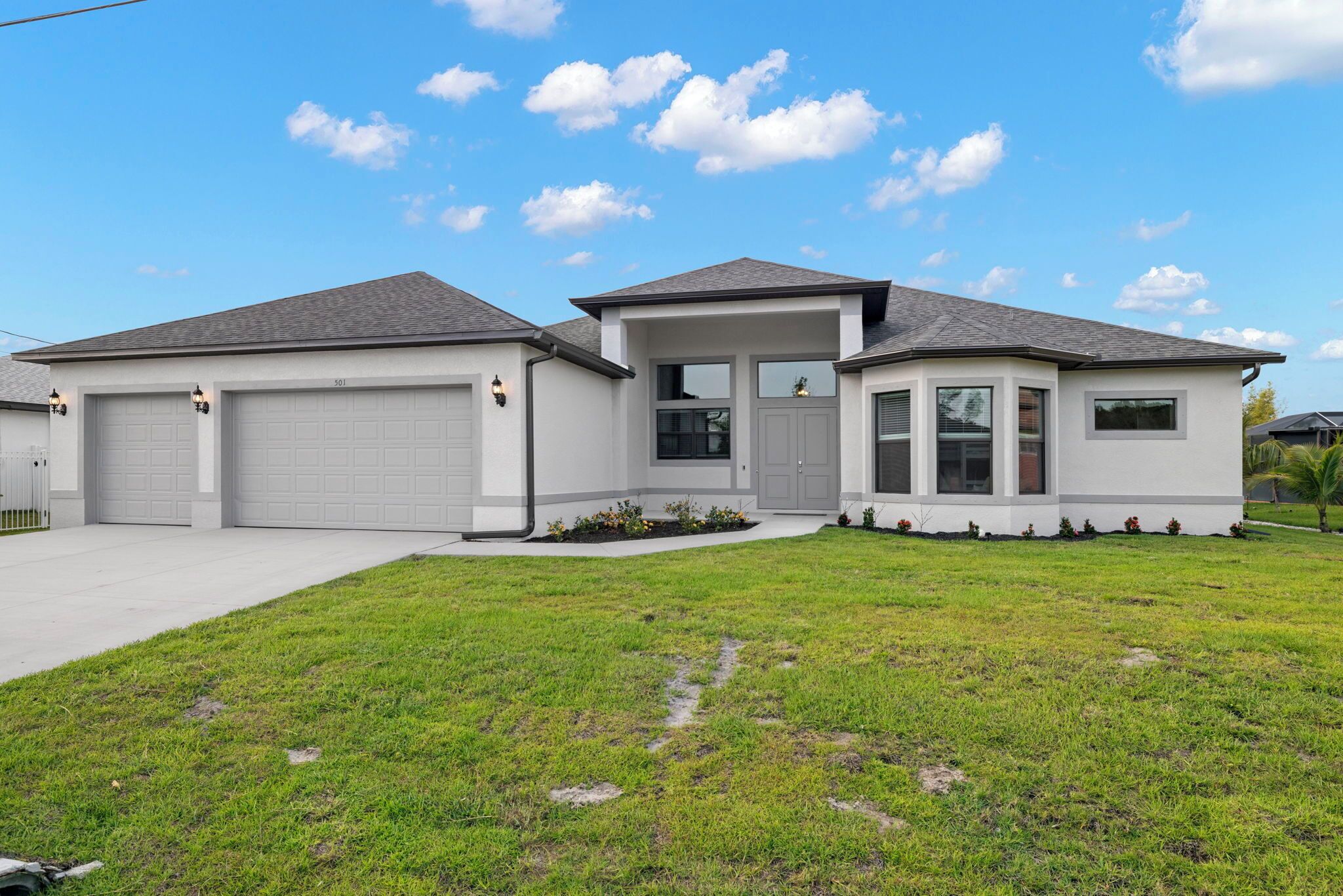 A modern two-story house with a garage, a covered porch, and a well-maintained lawn.