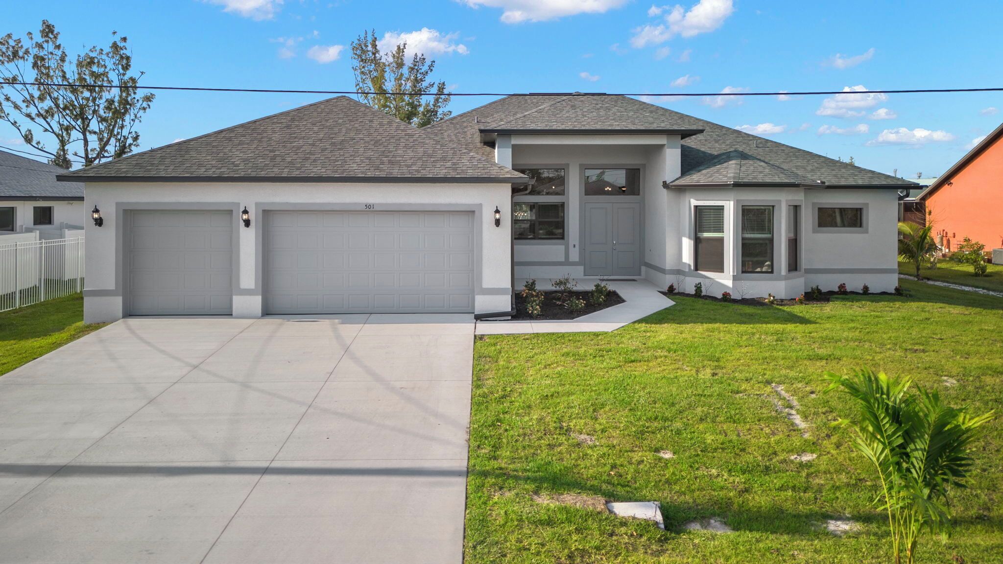 A modern two-story house with a garage, a well-maintained lawn, and a clear sky.