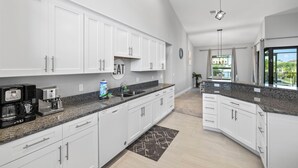 Eine moderne Küche mit weißen Schränken, Granit-Arbeitsplatten und einer integrierten Kaffeemaschine.