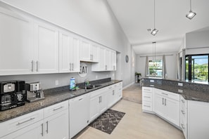A modern kitchen with white cabinets, granite countertops, and a built-in coffee maker.