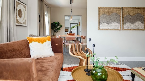 A living room with a brown sofa, a coffee table with a green vase, and a dining area in the background. - La Vie Boheme, Cozy, Minutues to Coconut Grove (Miami)