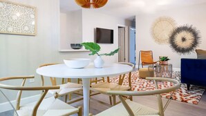 A modern dining area with a round table, chairs, and a hanging light fixture.