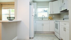 A modern kitchen with white cabinets, a built-in microwave, and a dishwasher.