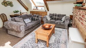 Ein gemütliches Loft-Wohnzimmer mit zwei grauen Sofas, einem Holztisch und einem Kamin aus Backstein.