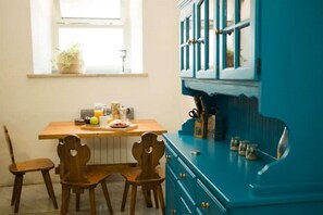A kitchen with a wooden table, chairs, and a blue cabinet with drawers. - Rome Trastevere Holidays Apartment (Roma)