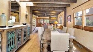 A dining area with a long wooden table, chairs, and a rustic wooden ceiling. - Finca Mapache by Kokopelli Property Management (Santa Fe)