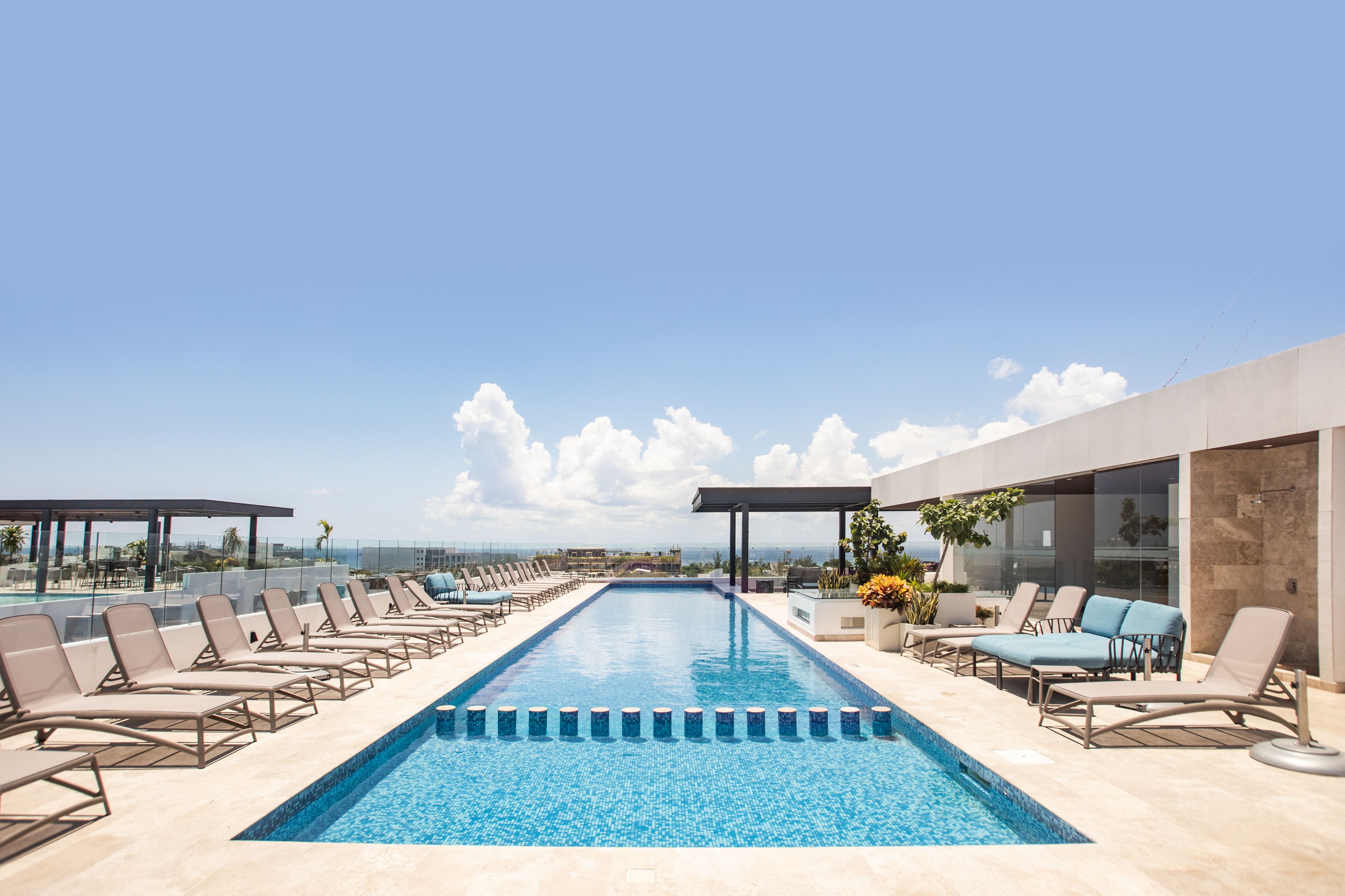 A rooftop pool with lounge chairs and a clear view of the ocean.