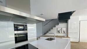 Une cuisine moderne dotée d’appareils électroménagers intégrés, d’une hotte en acier inoxydable et d’un élégant escalier.