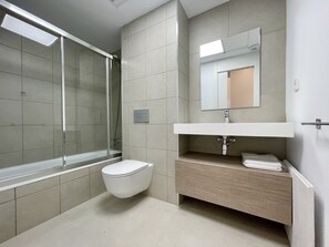 A modern bathroom with a glass shower enclosure, a toilet, and a vanity with a mirror. - ALLON BAY DUPLEX (R131) (Villajoyosa)