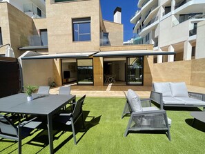 A modern outdoor patio with a dining area, lounge chairs, and a covered seating area. - ALLON BAY DUPLEX (R131) (Villajoyosa)