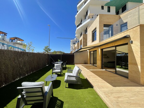 A modern outdoor patio with artificial grass, seating, and a building with balconies. - ALLON BAY DUPLEX (R131) (Villajoyosa)