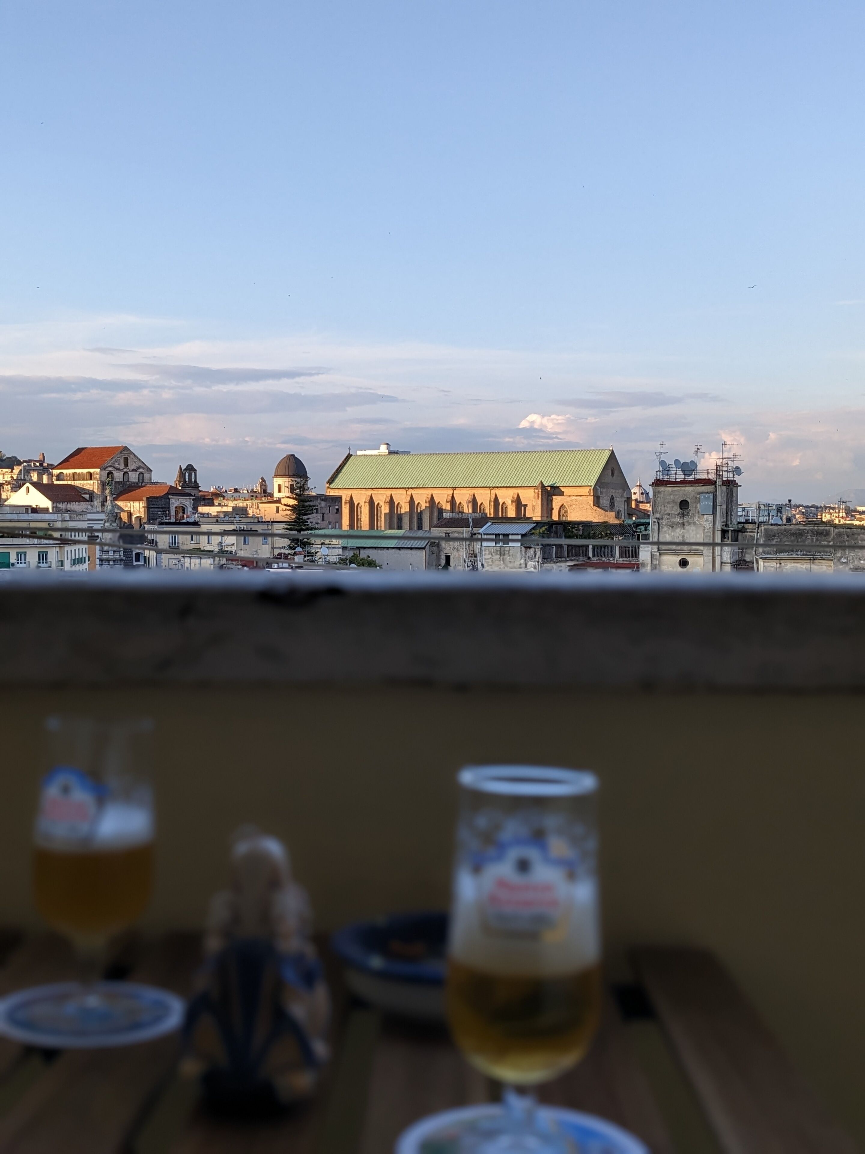 Una terraza con vista a un edificio histórico de techo verde y múltiples cúpulas.