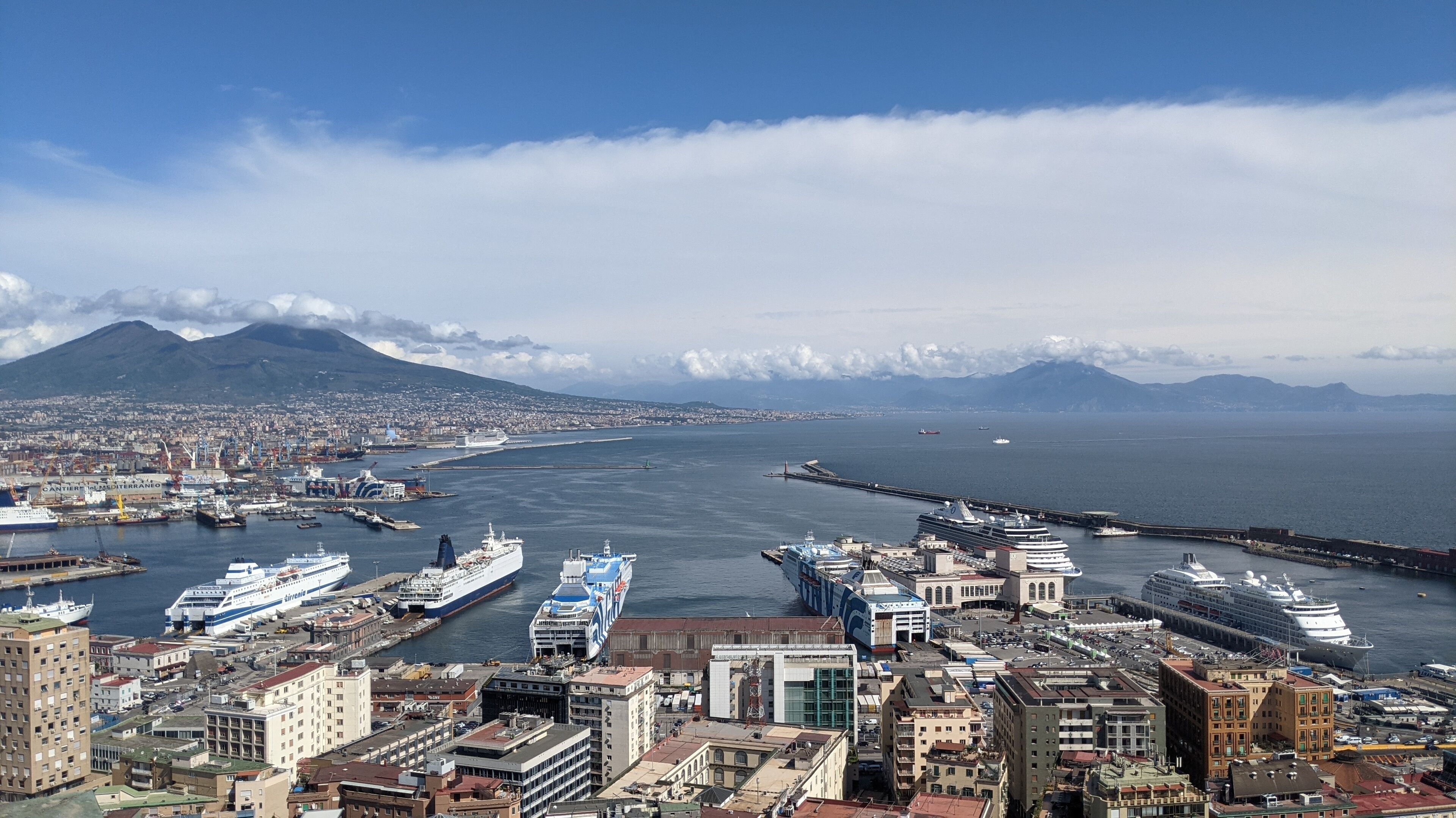 Un paisaje urbano costero con un puerto destacado, que incluye cruceros y un gran barco atracado en el muelle.