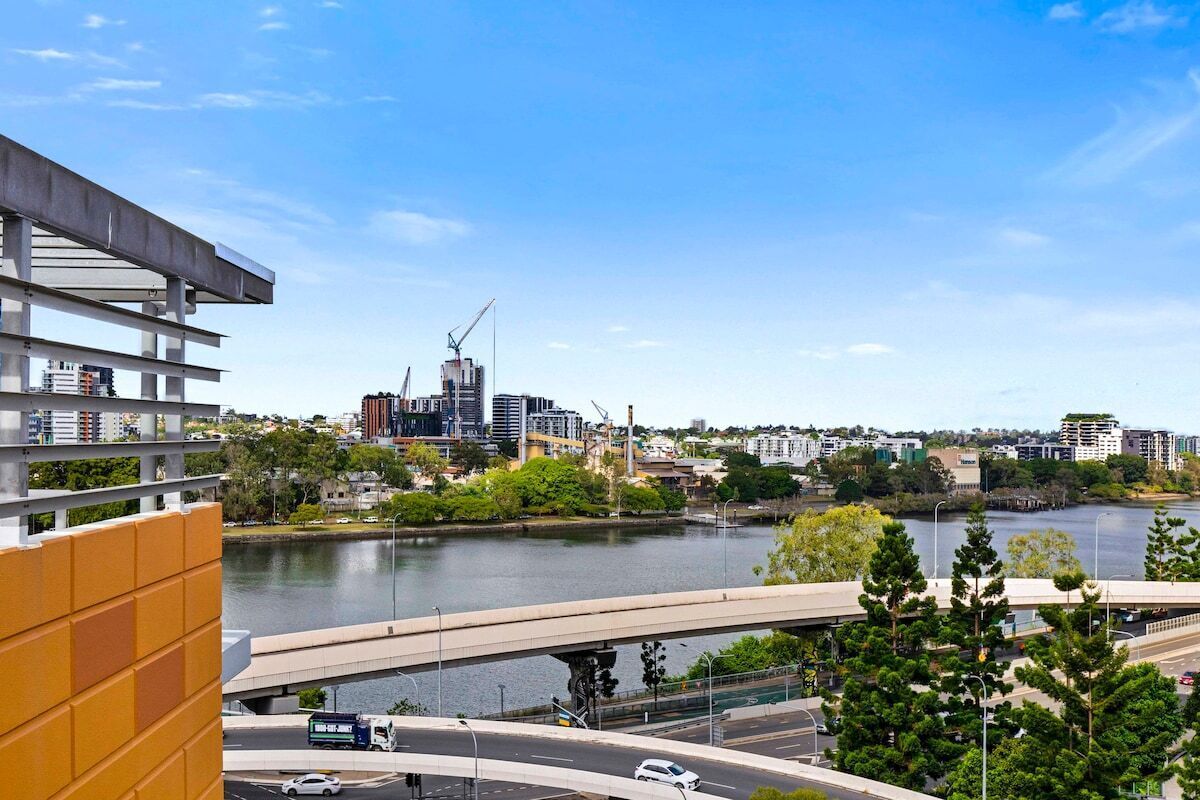 A cityscape with a river, modern buildings, and a bridge.