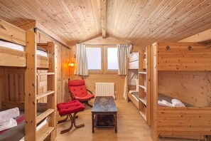 Une cabine avec des lits superposés, une chaise rouge, une petite table et une fenêtre avec des rideaux.