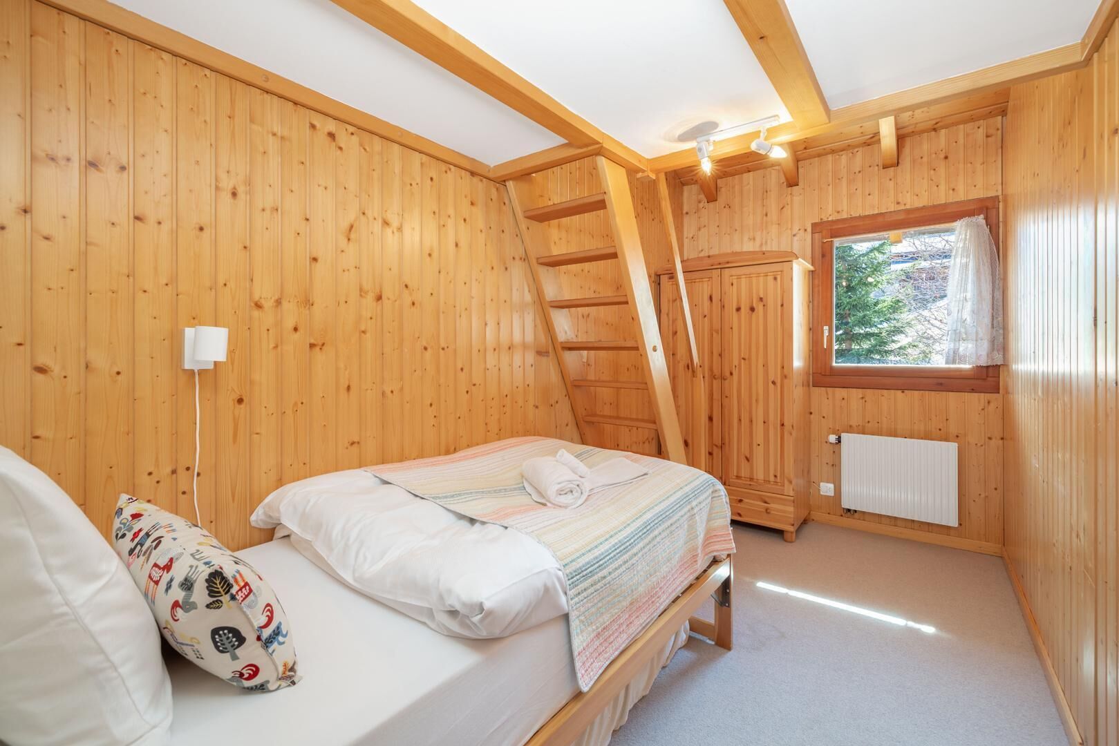 Una stanza accogliente in legno con un letto, una finestra vista e un termosifone.