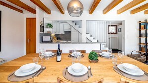 A dining room with a wooden table set for six, a wine bottle, and a small plant centerpiece. - Chalet Theo |Family retreat | Contemporary design (Riddes)